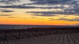 sunset at Race point with rippling ocean waves, and gray clouds sand fence between ocen and beach